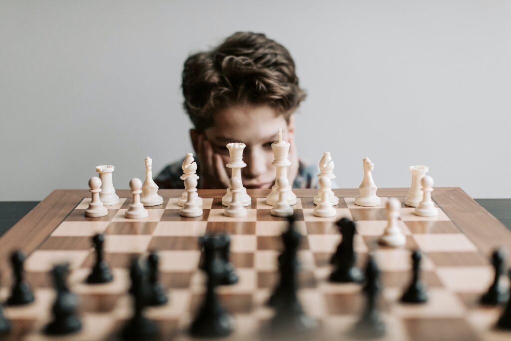 A young boy appears to be thinking while looking at a chess board